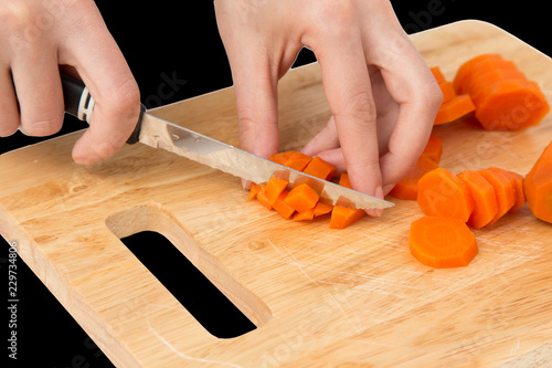 cook cuts carrots on a board on a black background
