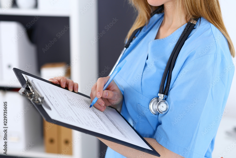 Female doctor filling up medical form on a clipboard, closeup. Healthcare, insurance and medicine concept Female doctor filling up medical form on a clipboard, closeup. Healthcare, insurance and medicine concept
