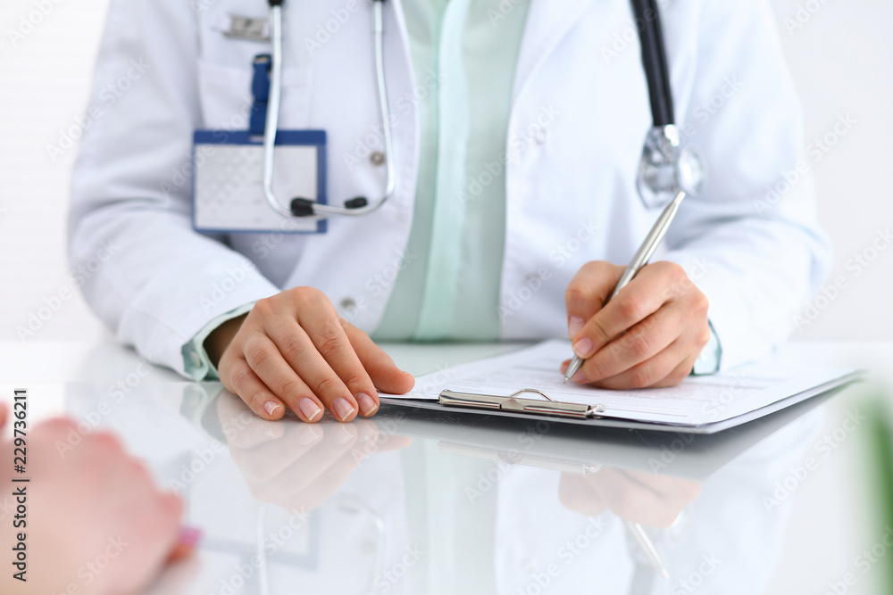 Doctor woman consulting patient while filling up an application form at the desk in hospital. Just hands close-up. Medicine and health care concept Doctor woman consulting patient while filling up an application form at the desk in hospital. Just hands close-up. Medicine and health care concept