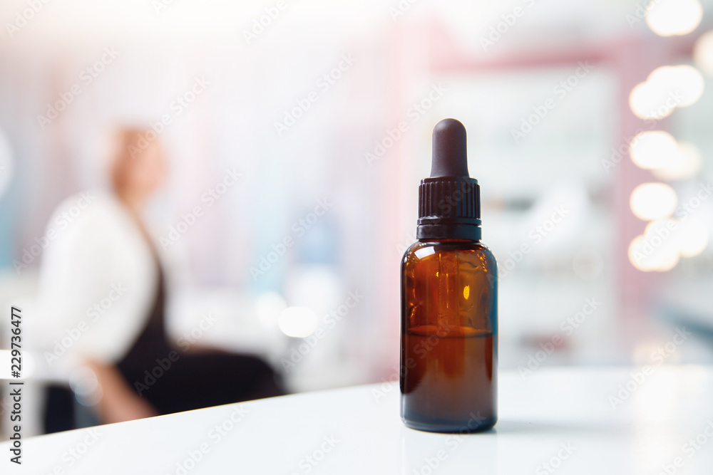 oil for hair and skin care in bottle with dispenser, background client spa salon is sitting chair. oil for hair and skin care in bottle with dispenser, background client spa salon is sitting chair.