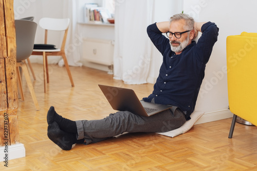 Man relaxing in his socks at home with a laptop © contrastwerkstatt