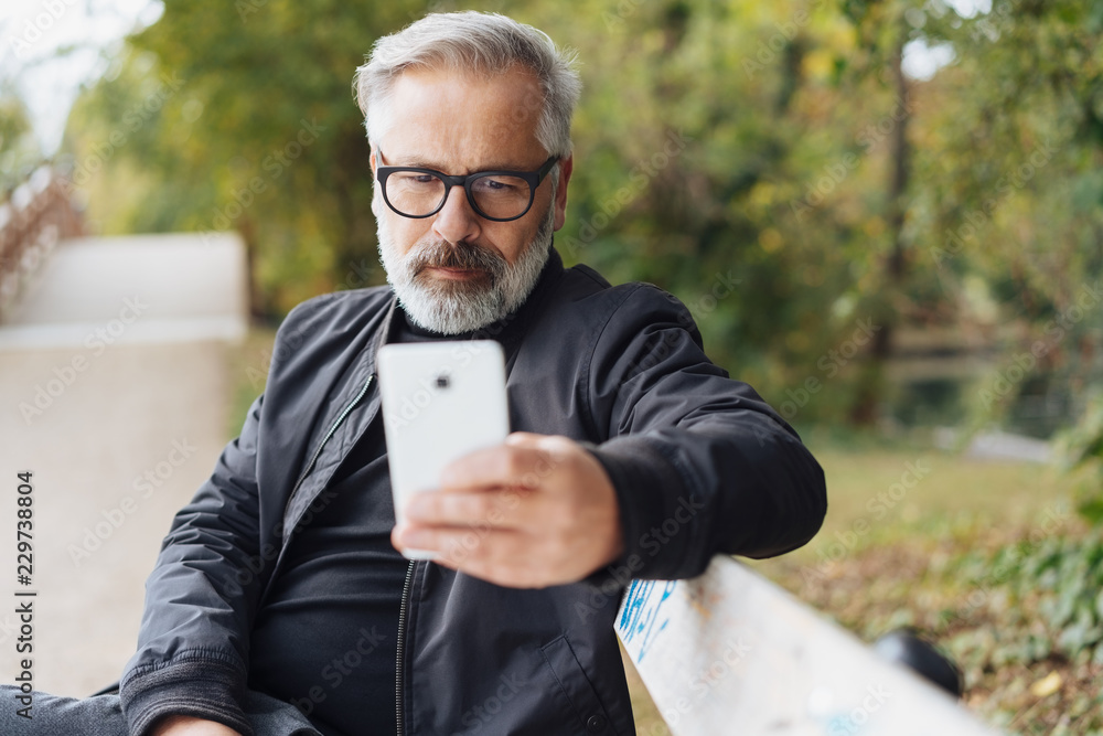 Thoughtful senior man using a mobile outdoors Thoughtful senior man using a mobile outdoors