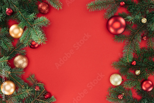 flat lay with pine tree branches with red and golden christmas balls isolated on red