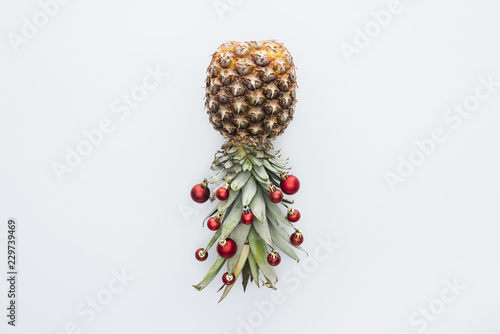 top view of red christmas balls on fresh pineapple isolated on white