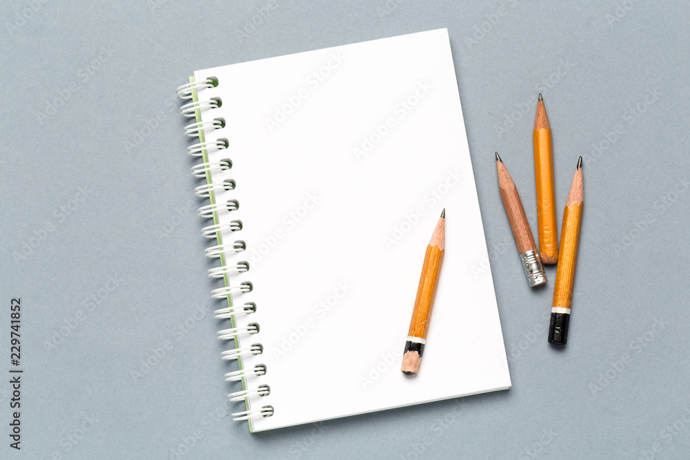 Pencils and notepad paper sheets on gray desk table