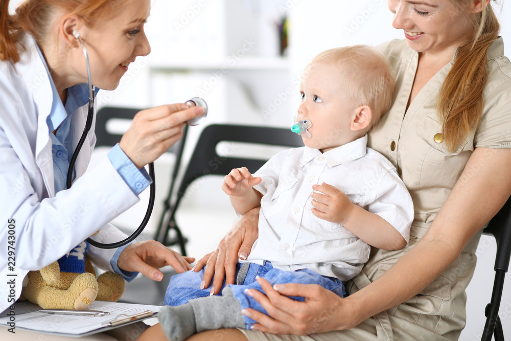 Doctor examining a little boy with stethoscope. Mother holds her son on her lap. Motherless and medicine concept Doctor examining a little boy with stethoscope. Mother holds her son on her lap. Motherless and medicine concept