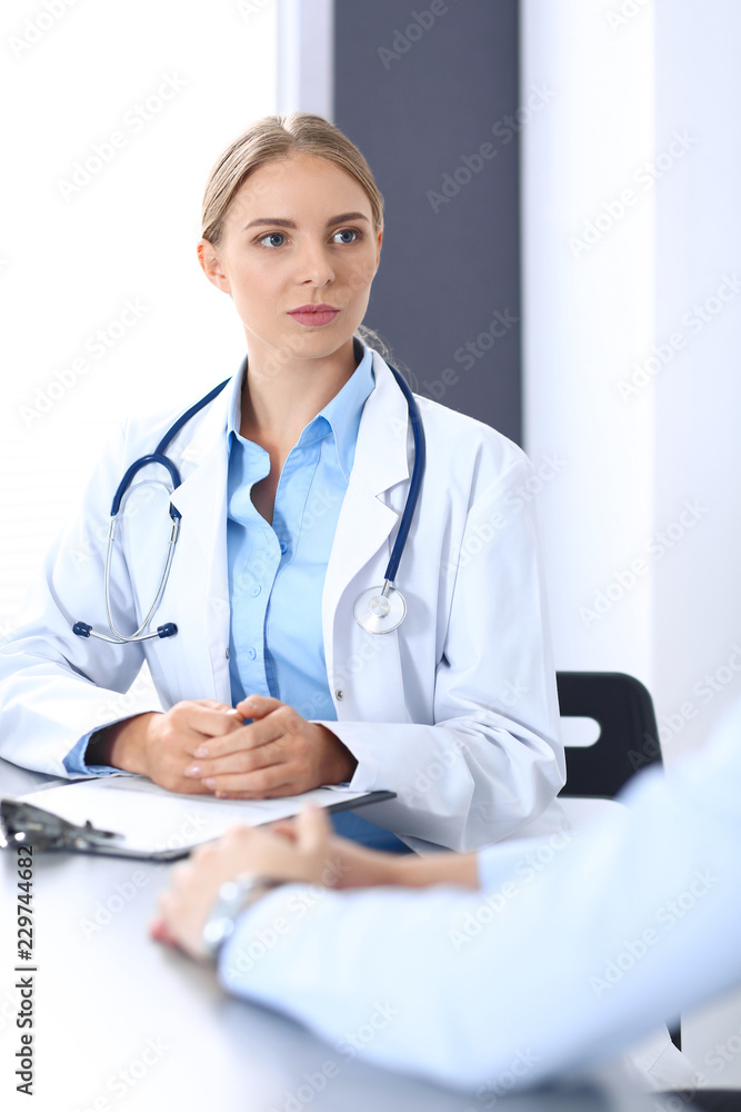 Doctor and patient in hospital. Beautiful blonde physician consulting business man about his health. Medicine concept Doctor and patient in hospital. Beautiful blonde physician consulting business man about his health. Medicine concept