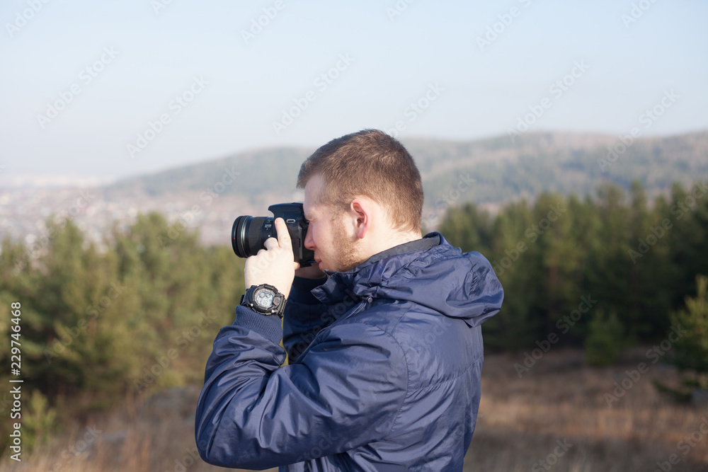 Nature photographer with digital camera on top of the mountain