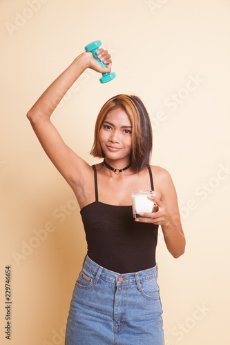 Healthy Asian woman drinking a glass of milk and dumbbell.