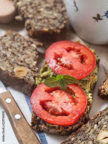 Flourless bread with sunflower, flax and chia seeds, oats, psyllium seed husks and hazelnuts, served with pesto and fresh tomatoes photo