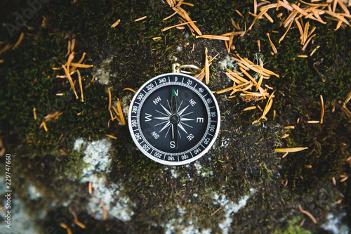 Fotografía Magnetic compass with a black dial on a wild stone covered with green moss