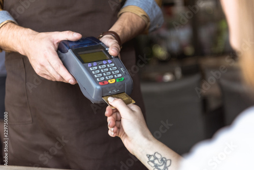 cropped shot of waiter holding payment terminal while customer inserting credit card