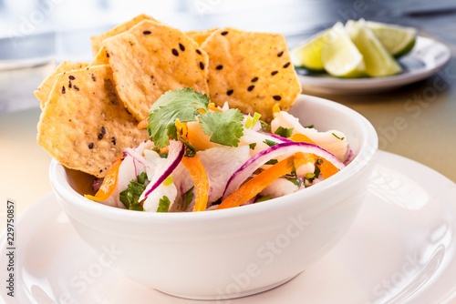 Corvina fish marinated with lemon, red onions, yellow peppers and sesame seed chips photo