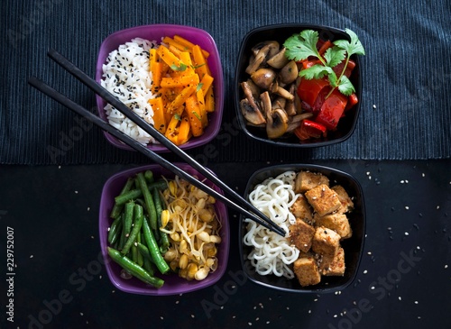 Four bowls with rice, roasted carrots, mushrooms, peppers, beans, mung beans, Mie noodles and tofu (Vegan)