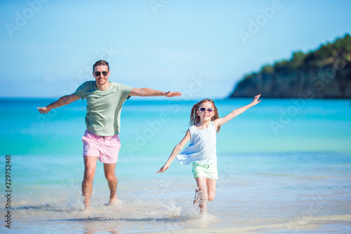 Family at tropical beach walking together on tropical Carlisle bay beach with white sand and turquoise ocean water at Antigua island in Caribbean.