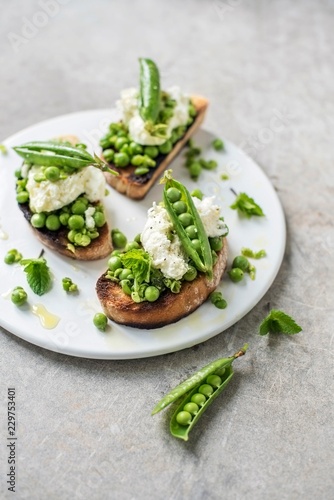 Bruschetta with green peas and mozzarella on plate photo