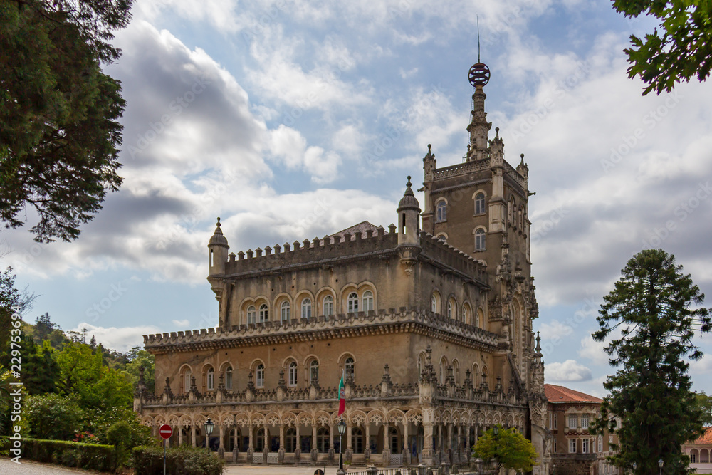 Obraz premium The Bussaco Palace Hotel under a blue sky with white clouds