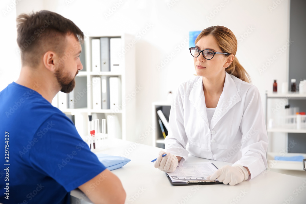 Female doctor filling in document before blood draw of male patient in clinic Female doctor filling in document before blood draw of male patient in clinic