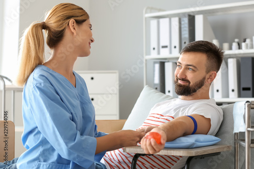 Foto Female nurse preparing male donor for blood transfusion in hospital