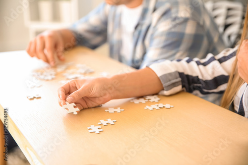 Young people assembling puzzle on wooden table
