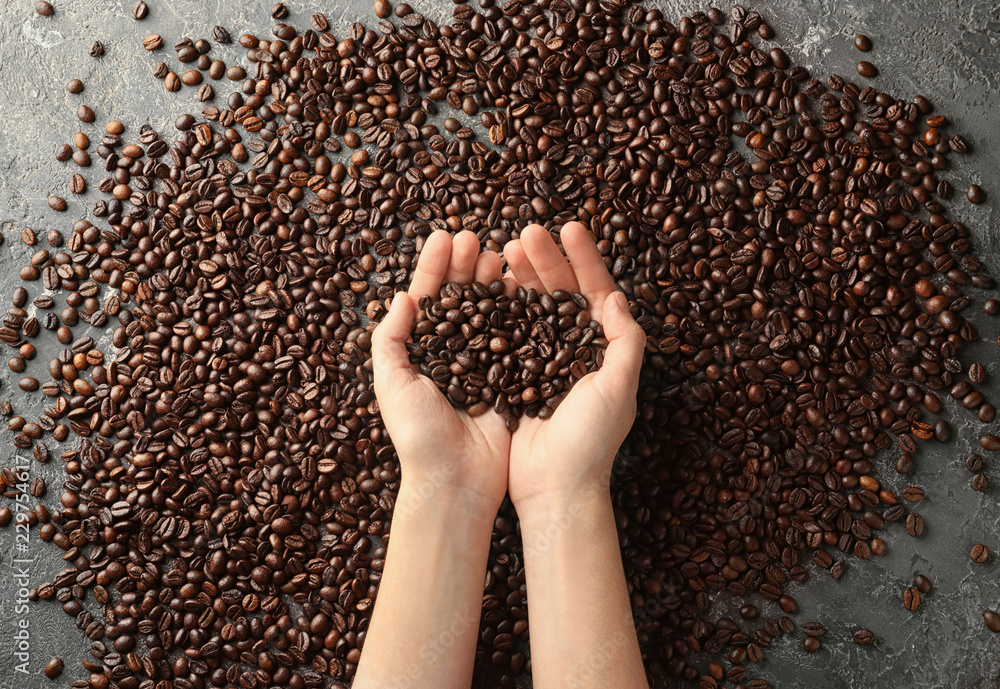 Female hands with coffee beans on grey background Female hands with coffee beans on grey background
