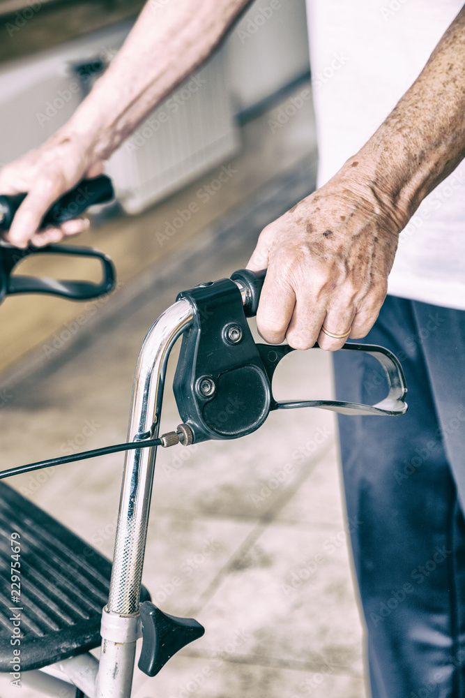 Elderly man with walker moving at the hospital, detail on hands