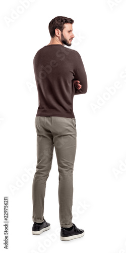 Foto An adult bearded man in casual sweater stands in a back view half turned to look behind his shoulder