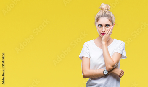 Young beautiful blonde woman wearing white t-shirt over isolated background thinking looking tired and bored with depression problems with crossed arms. © Krakenimages.com