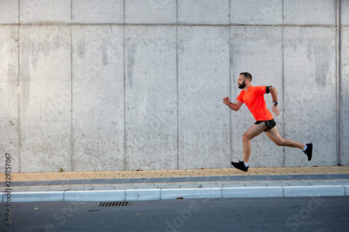 Young bearded man running on the street. Healthy lifestyle concept.