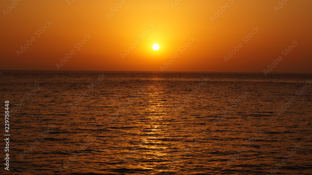 Sunset over Pacific Carribean beach showing dramatic red and yellow sky as sun sets 