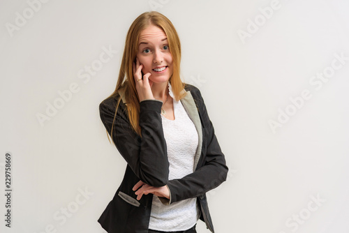 Studio portrait on the camera of a smiling beautiful girl with long hair talking on a white background with emotions.