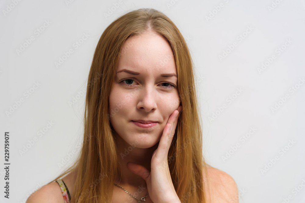 Studio portrait on the camera of a smiling beautiful girl with long hair talking on a white background with emotions. Studio portrait on the camera of a smiling beautiful girl with long hair talking on a white background with emotions.