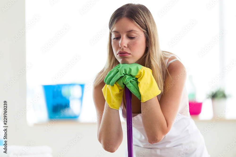 Boring young woman holding broom while cleaning at home. Boring young woman holding broom while cleaning at home.
