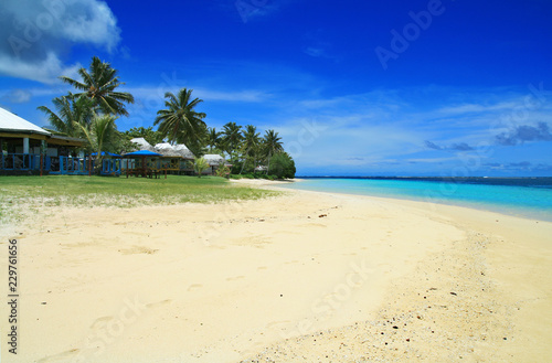 Fototapeta Naklejka Na Ścianę i Meble -  White golden sandy beach and coral blue sea waters with Polynesian beach front houses- traditional fale in Samoa Manase Beach in Pacific Ocean