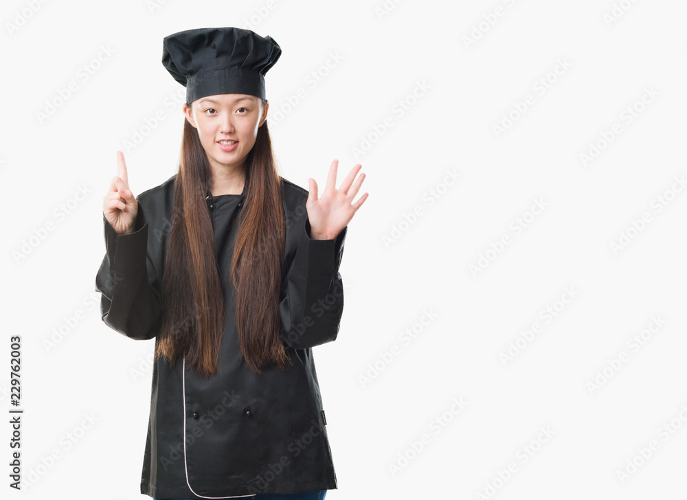 Young Chinese woman over isolated background wearing chef uniform showing and pointing up with fingers number six while smiling confident and happy. Young Chinese woman over isolated background wearing chef uniform showing and pointing up with fingers number six while smiling confident and happy.