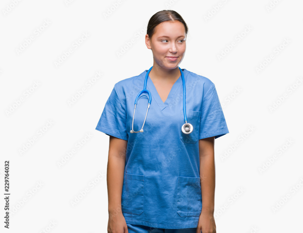 Young caucasian doctor woman wearing medical uniform over isolated background smiling looking side and staring away thinking. Young caucasian doctor woman wearing medical uniform over isolated background smiling looking side and staring away thinking.