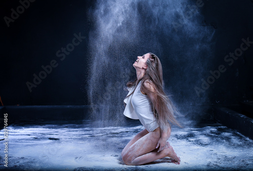 sporty young girl throws flour on black background