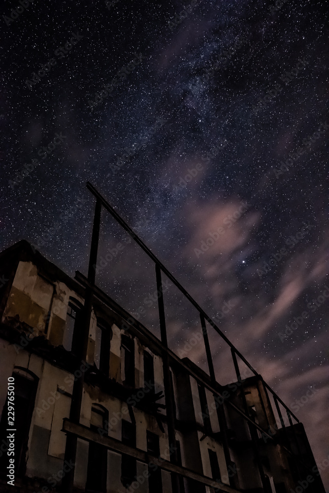 Night sky and the Milky Way over the old abandoned house