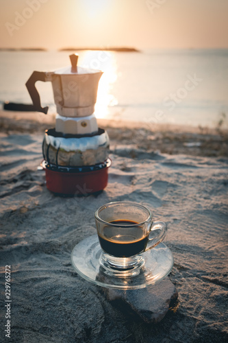 black coffee ready to drink from mug on the beach outdoor picnic..