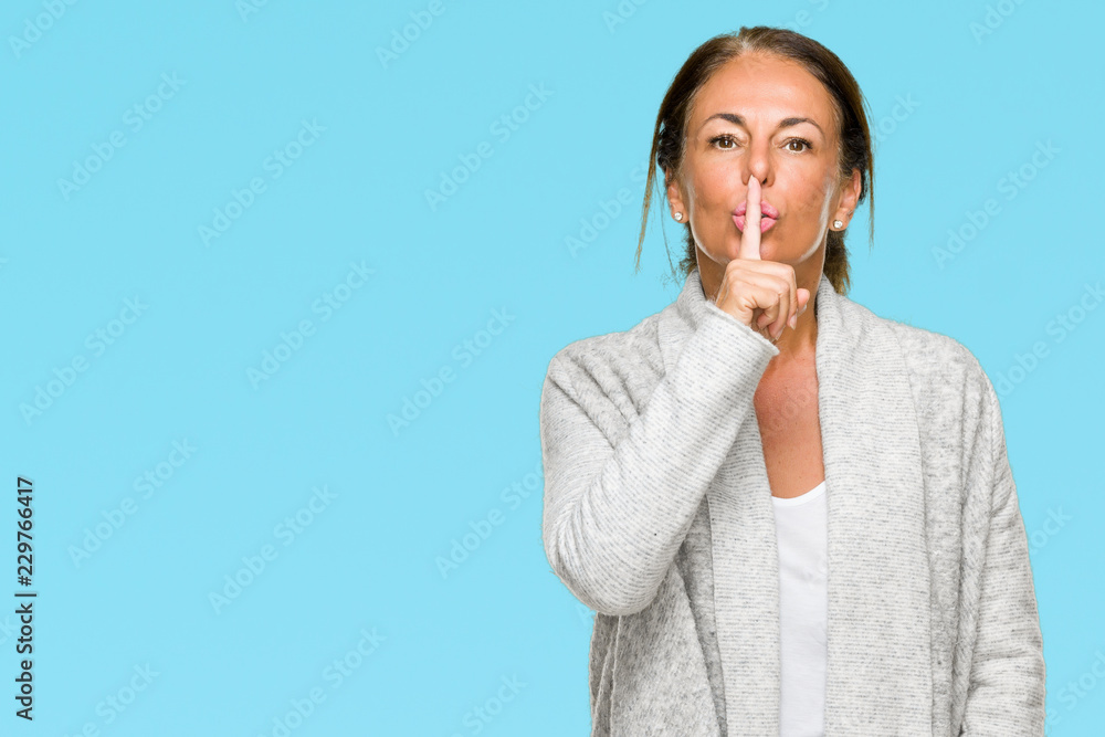 Beautiful middle age adult woman wearing winter sweater over isolated background asking to be quiet with finger on lips. Silence and secret concept. Beautiful middle age adult woman wearing winter sweater over isolated background asking to be quiet with finger on lips. Silence and secret concept.