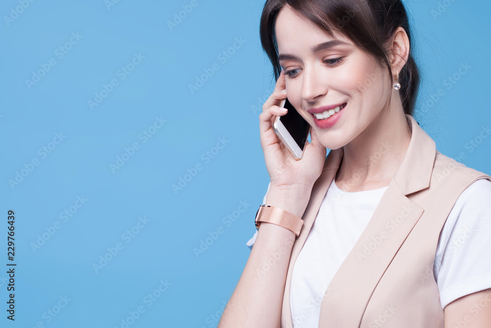 Beautiful successful young business woman uses phone on blue background Beautiful successful young business woman uses phone on blue background