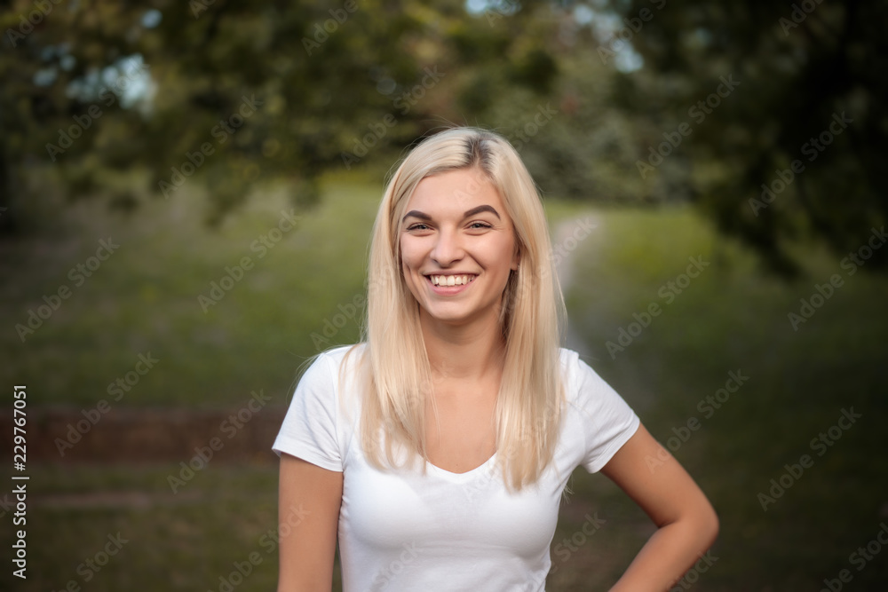 Beautiful young cute woman standing on grass in nature green park with beautiful sundown light looking camera. Beautiful young cute woman standing on grass in nature green park with beautiful sundown light looking camera.