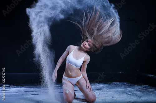 sporty young girl throws flour on black background