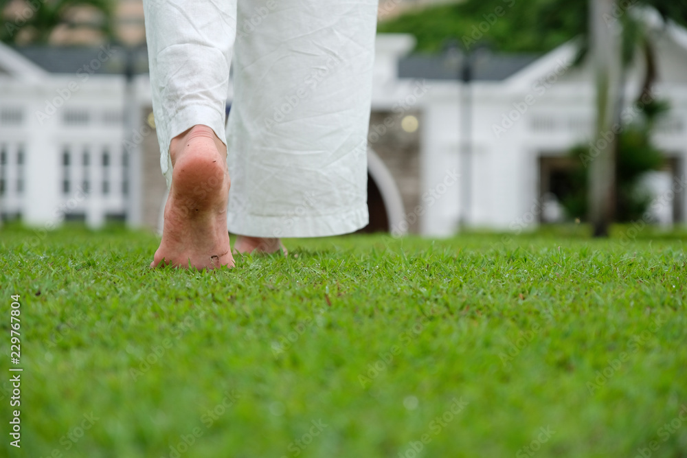 close up a barefoot woman walking on the grass in front home garden in the relax time