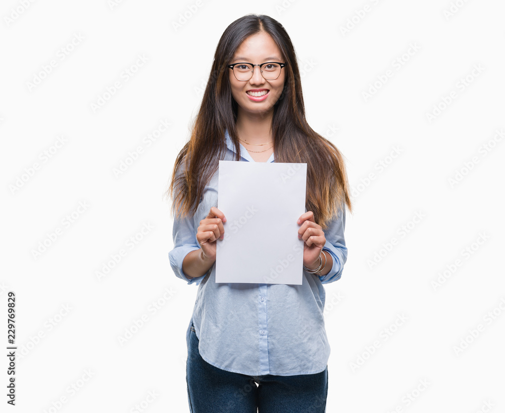 Young asian woman holding blank paper over isolated background with a happy face standing and smiling with a confident smile showing teeth Young asian woman holding blank paper over isolated background with a happy face standing and smiling with a confident smile showing teeth