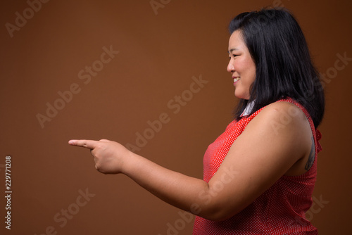 Profile view of beautiful overweight Asian woman pointing finger