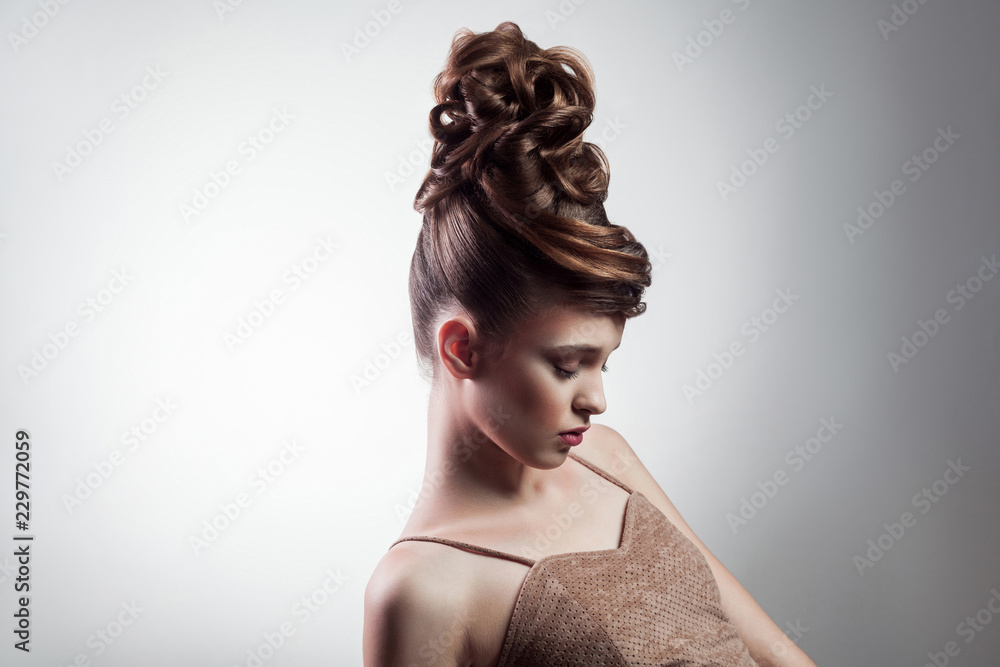 portrait of attractive brunette woman with stylish hairdo and makeup posing with closed eyes on isolated grey background. indoor, studio shot on copy space.