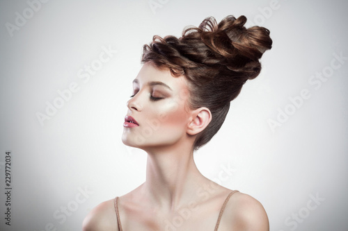 portrait of attractive brunette woman with stylish hairdo and makeup posing with closed eyes on isolated grey background. indoor, studio shot on copy space.
