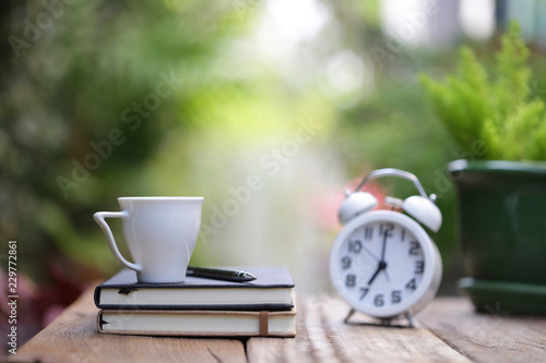 white cup and notebook with clock on wooden table