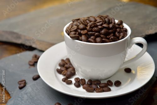 Cup full of coffee beans on the stone.